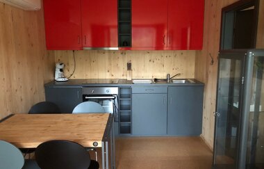 Eine Küchenzeile in rot und grau, ein Tisch mit Stühlen und ein Kühlschrank stehen im Wohnraum | © Touristikgemeinschaft Hohenlohe e. V.| Katharina Schmieg
