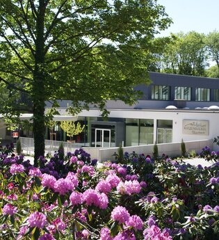 Blick auf Gebäude, die Katzenbuckel-Therme, davor eine Blumenfeld mit rosa und lila farbenen Blumen. Waldbrunn im Odenwald. | © Gemeinde Waldbrunn