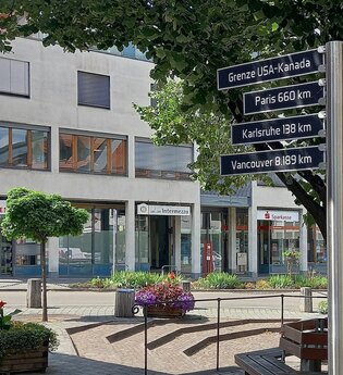 Ein Marktplatz in Gaildorf mit einem Wegweiser, der Entfernungen zu verschiedenen Städten und Ländern anzeigt. | © Petra Natzkowski