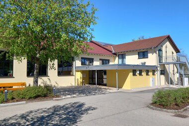 Hellgelbes zweistöckiges Gebäude mit Flachdachvorbau und Metalltreppe ins zweite OG | © Petra Natzkowski