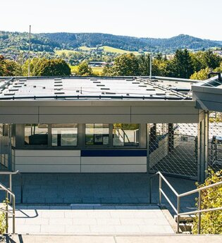 Eingangsbereich eines modernen Freibads mit grüner Umgebung und Hügeln im Hintergrund. | © Stuttgart-Marketing GmbH, Sarah Schmid