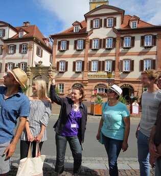 Blick auf eine Gruppe Menschen auf dem Bad Mergentheimer Marktplatz. Im Hintergrund sind die Zwillingshäuser zu sehen. | © Stadt Bad Mergentheim