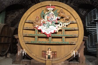 Im Museum steht ein großes altes Weinfass, davor sind Kerzen angezündet | © Touristikgemeinschaft Hohenlohe e. V. | Marion Schlund