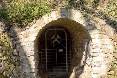 Steinernes Tor mit Gitter und der Aufschrift "Hülfe Gottes" aus 2009 in bewachsenem Gelände. | © Roland Robra / Tourismus Service Bergstrasse Burgensteig