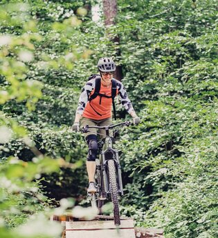 Eine Mountainbikerin fährt auf ihrem Bike auf einem Trail durch den Wald | © Touristikgemeinschaft Odenwald e.V.