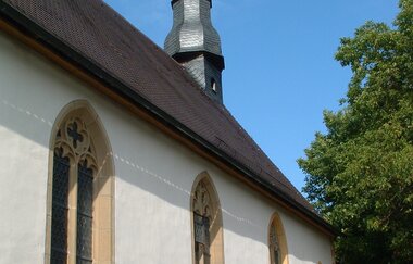 Die Kapelle hat einen langen Turm und ist von einem Baum umgeben | © Touristikgemeinschaft Hohenlohe e. V. | Marion Schlund