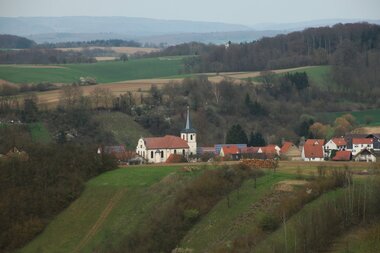 Das Dörfchen Balzfeld mit markantem Kirchturm im Vordergrund dahinter schemenhaft erkennbar die Erhebungen des Odenwalds. | © Landratsamt Rhein-Neckar-Kreis